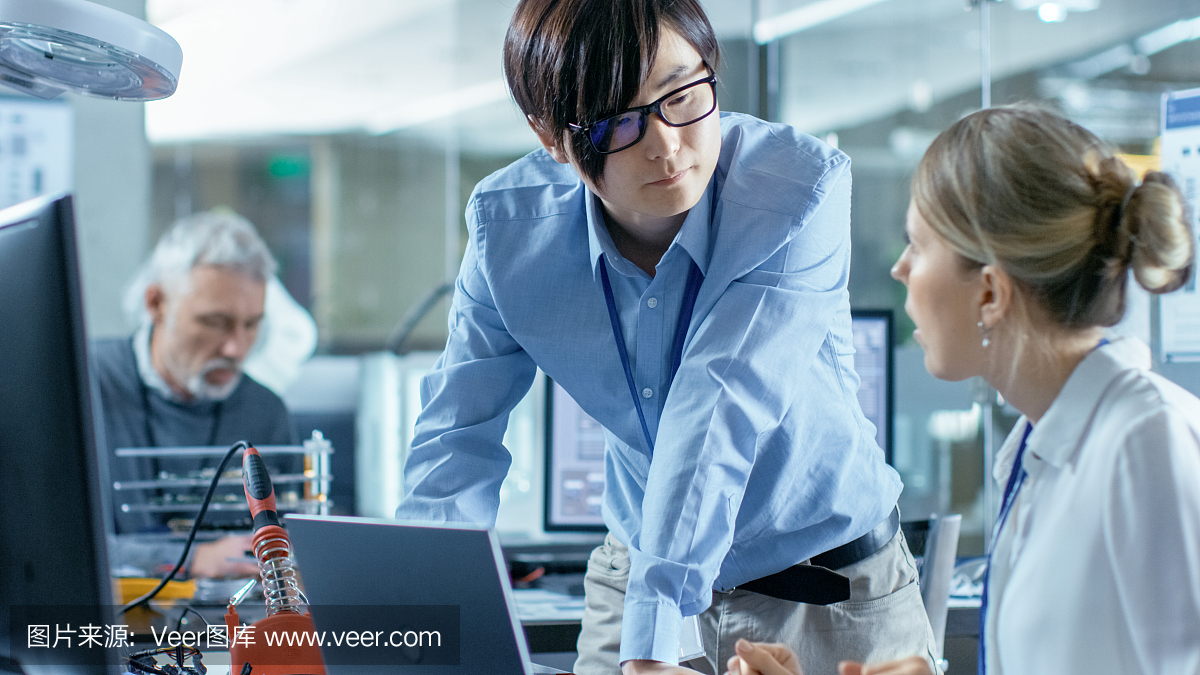 女計算機科學家用綠色屏幕模型連接電路板到她的筆記本電腦。她在先進技術實驗室工作。