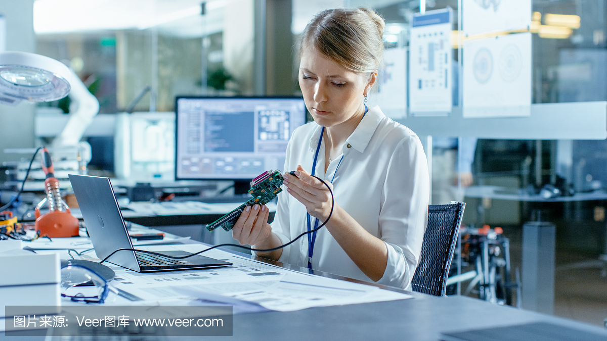 女計算機科學(xué)家將電路板連接到她的筆記本電腦并開始編程。她在先進(jìn)技術(shù)實驗室工作。